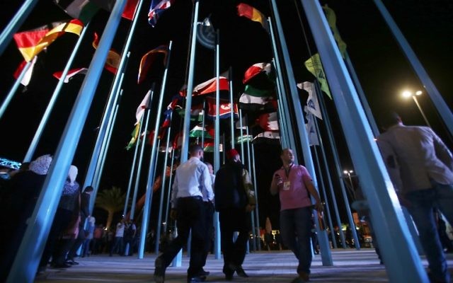Participants and visitors walk past flags of various countries during the opening of the Damascus International Fair late on August 17, 2017, in the Syrian capital. (AFP/Youssef KARWASHAN)