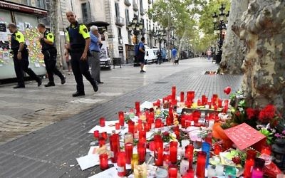 Police officers walk by tributes left for victims of the Barcelona attack, on the Las Ramblas boulevard in Barcelona on August 19, 2017, two days after a van ploughed into the crowd, killing 13 persons and injuring over 100. (AFP PHOTO / Pascal GUYOT)