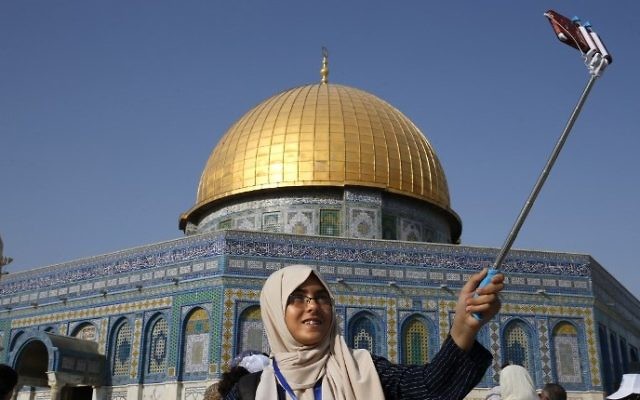 A Palestinian girl from the Gaza Strip takes a selfie outside the Dome of the Rock mosque in the Al-Aqsa mosque compound in Jerusalem's old city on August 20, 2017 as she visits the city for the first time as part of an exchange program run by the UN agency for Palestinian refugees. (AFP PHOTO / AHMAD GHARABLI)