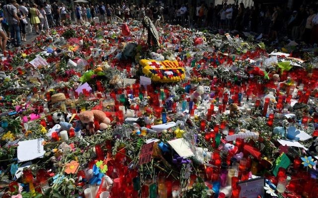 People display flowers and candles to pay tribute to the victims of the Barcelona and Cambrils attacks on the Rambla boulevard in Barcelona on August 22, 2017, five days after the attacks that killed 15 people. (AFP PHOTO / LLUIS GENE)