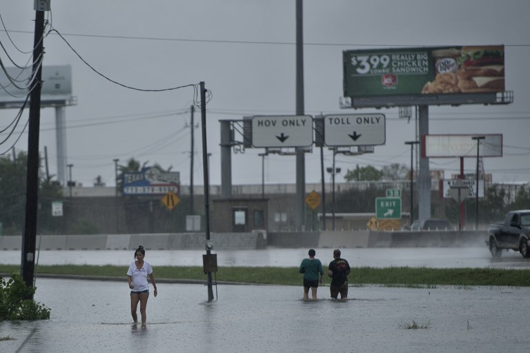 People walk through flooded streets during the aftermath of Hurricane Harvey August 27, 2017 in Houston, Texas. (AFP PHOTO / Brendan Smialowski)