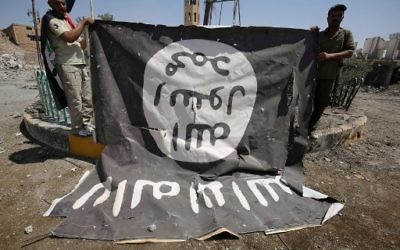 Fighters from the Hashed al-Shaabi (Popular Mobilisation units), backing the Iraqi forces, pose for a photograph with a flag of the Islamic State (IS) group in Tal Afar's Qalea central district during an operation to retake the city from the jihadists on August 27, 2017. (AFP Photo/Ahmad al-Rubaye)