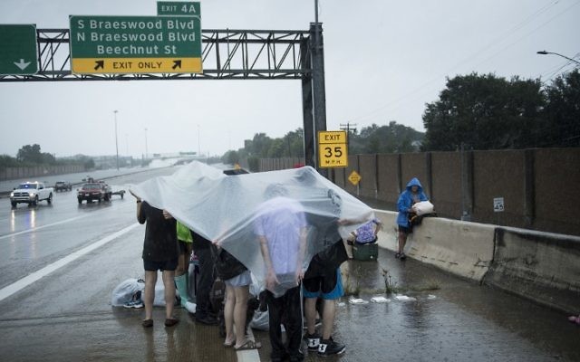 Evacuation residents from the Meyerland wait on an I-610 overpass for further help during the aftermath of Hurricane Harvey August 27, 2017 in Houston, Texas.(AFP PHOTO / Brendan Smialowski)