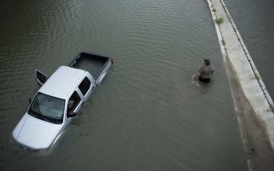 A truck driver walks past an abandoned truck while checking the depth of an underpass during the aftermath of Hurricane Harvey August 28, 2017 in Houston, Texas. (AFP PHOTO / Brendan Smialowski)