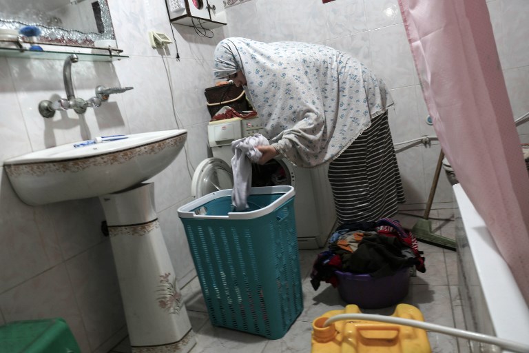 This photo taken on July 23, 2017 shows a Palestinian woman washing clothes during the few hours of mains electricity supply her house receives every day, at Rafah refugee camp in the southern Gaza Strip. (AFP PHOTO / SAID KHATIB)