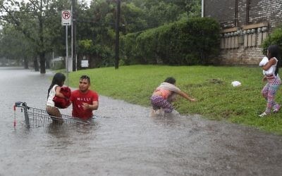 A man helps children across a flooded street as they evacuate their home in Houston August 27, 2017. (Joe Raedle/Getty Images/AFP)