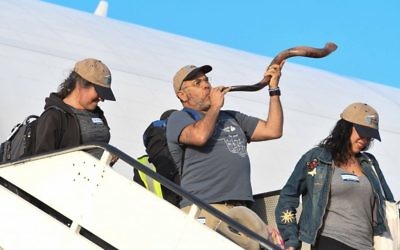 A new immigrant to Israel blows a shofar after landing at Ben Gurion Airport on Tuesday, August 15, 2017 (Shahar Azran) 