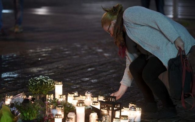 A woman places a memorial candle at the Market Square for the victims of Friday's stabbings in Turku, Finland, on Friday evening, Aug. 18, 2017. Several people were stabbed on the Market Square on Friday. (Vesa Moilanen/Lehtikuva via AP)