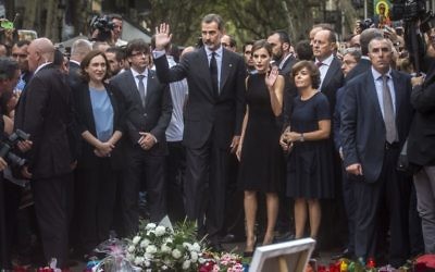 Spain's King Felipe and Queen Letizia wave to the crowd after paying respect at a memorial tribute of flowers, messages and candles to the van attack victims in Las Ramblas promenade, Barcelona, Spain on August 19, 2017. (AP Photo/Santi Palacios) 