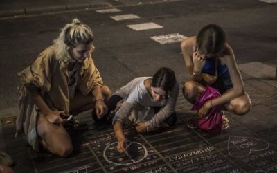 A girl draws a peace symbol on the street as a tribute to the victims of the terrorist attack, on the historic street of Las Ramblas, two day after the vehicle attacks, in Barcelona, Spain on August 18, 2017. (AP Photo/Santi Palacios) 