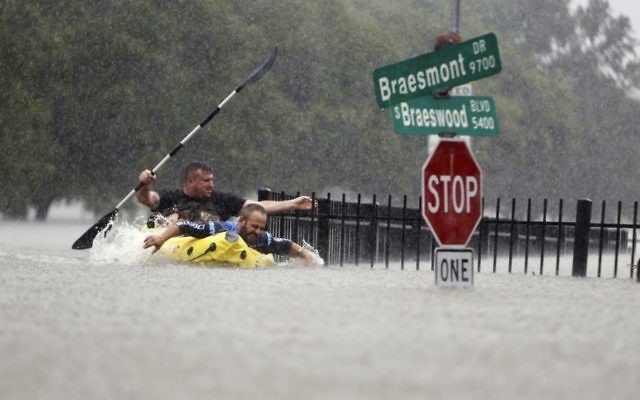 Two kayakers try to beat the current pushing them down an overflowing Brays Bayou from Tropical Storm Harvey in Houston, Texas, Sunday, Aug. 27, 2017. (Mark Mulligan/Houston Chronicle via AP)