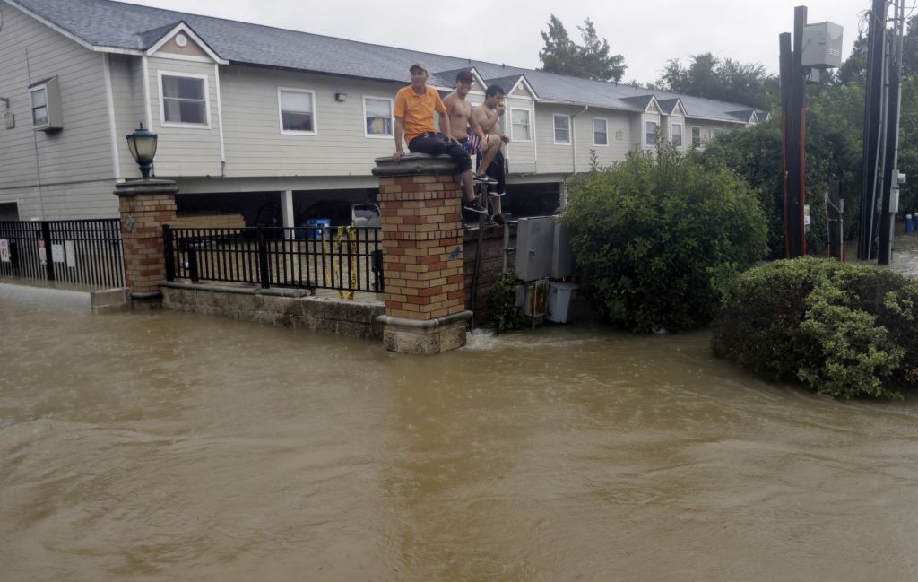 Residents sit on a fence surrounded by floodwaters from Tropical Storm Harvey on Sunday, Aug. 27, 2017, in Houston, Texas. (AP Photo/David J. Phillip)