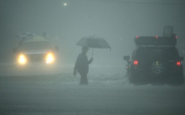 A man walks through floodwaters from Tropical Storm Harvey as he evacuates his home on Sunday, Aug. 27, 2017, in Houston, Texas. (AP Photo/Charlie Riedel)