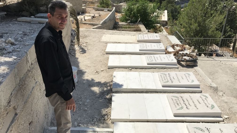 Hassan Dabash stands at the graves of his ex-wife and five children who were killed in a car accident in the West Bank on June 27, 2017. (Jacob Magid/Times of Israel)