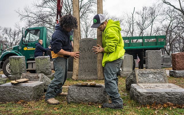 Workers placing headstones back on their bases at Chesed Shel Emeth Cemetery in the St. Louis area. (James Griesedieck)