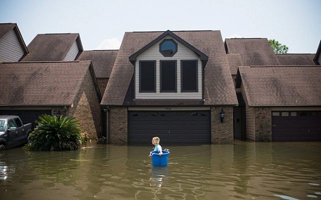 Jenna Fountain carries a bucket down Regency Drive to try to recover items from their flooded home in Port Arthur, Texas, September 1, 2017. (AFP PHOTO/ Emily Kask)