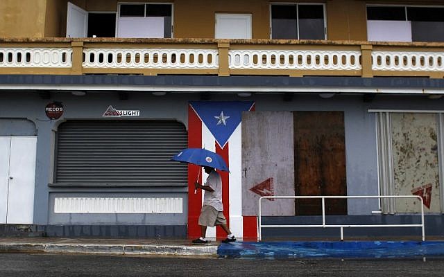 A man with an umbrella walks on a sidewalk as Hurricane Irma approaches in Luquillo, Puerto Rico, on September 6, 2017. (AFP Photo/Ricardo Arduengo)
