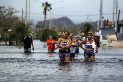 People walk on a flooded street in the aftermath of Hurricane Maria in San Juan, Puerto Rico on September 22, 2017. (AFP PHOTO / Ricardo ARDUENGO)