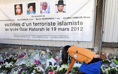 This file photo taken on March 25, 2012, in Toulouse, southwestern France, shows France's Jewish scout placing flowers under a banner paying tribute to the victims of jihadist Mohammed Merah who killed three children and a teacher at the 'Ozar Hatorah' Jewish school. (AFP/Eric Cabanis)