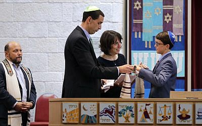 Jason Yustein and Gabi Moses hold their son Doran's hands during a Bar Mitzvah in the aftermath of Harvey Saturday, Sept. 2, 2017, in Houston. (AP Photo/David J. Phillip)