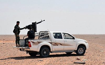 This photo released on Monday, Sept 4, 2017 by the Syrian official news agency SANA, shows Syrian troops and pro-government gunmen standing on pickup trucks with heavy machine-guns mounted on them, in the eastern city of Deir el-Zour, Syria. (SANA via AP)