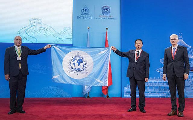 A Palestinian delegate receives the Interpol flag from the president of the International Criminal Police Organization Meng Hongwei, second right, during the Interpol General Assembly, in Beijing, China, September 27, 2017. (Interpol via AP)