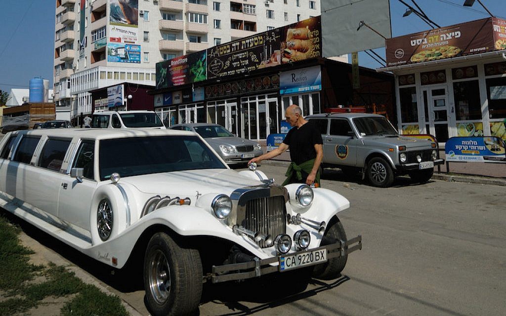 An Israeli visitor to Uman examining a Ukrainian luxury limousine parked on the city’s heavily Jewish Pushkin Street, September 8, 2017. (Cnaan Liphshiz/via JTA)