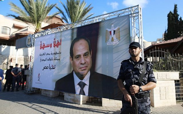 A Hamas fighter stands next to a billboard bearing a portrait of Egyptian President Abdel-Fattah el-Sissi near the Palestinian government headquarters in Gaza City on October 3, 2017. (AFP Photo/Mohammed Abed)