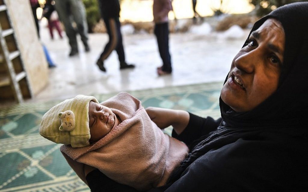 A woman, who along with members of her family was used as human shields by Islamic State (IS) group fighters, holds a new born baby after fleeing from the center of Raqqa, Syria, October 6, 2017. (AFP//BULENT KILIC)