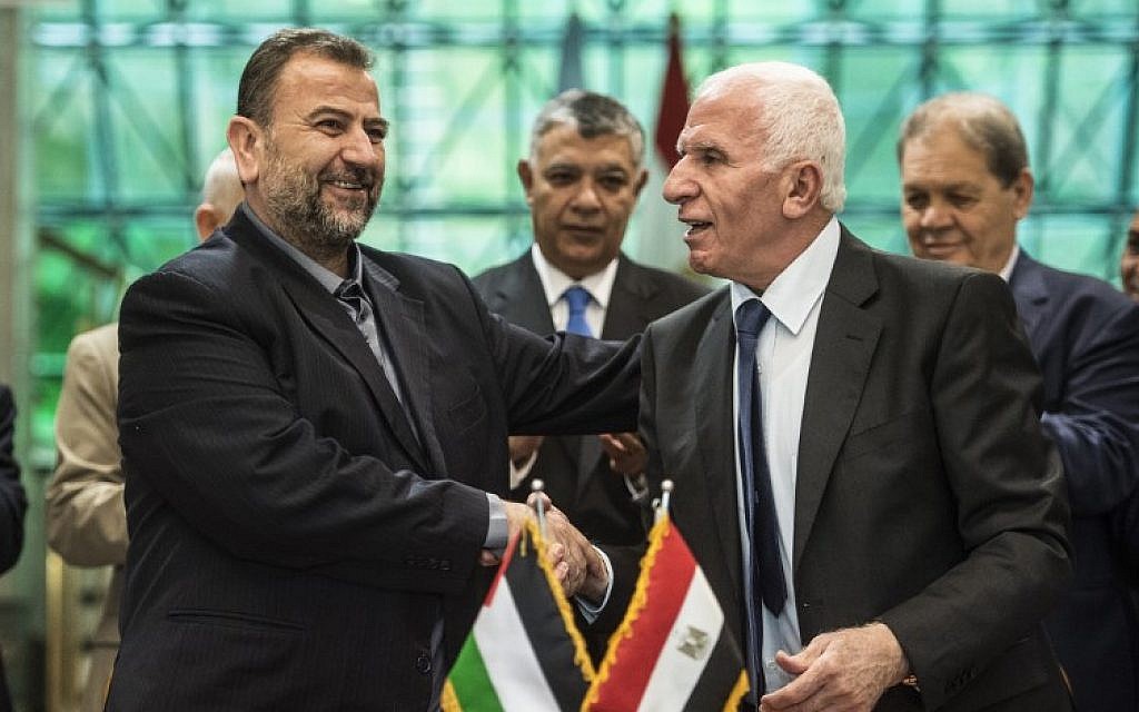 Fatah's Azzam al-Ahmad, right, and Saleh al-Arouri, left, of Hamas shake hands after signing a reconciliation deal in Cairo on October 12, 2017, as the two rival Palestinian movements ostensibly ended their decade-long split following negotiations overseen by Egypt. (AFP/Khaled Desouki)