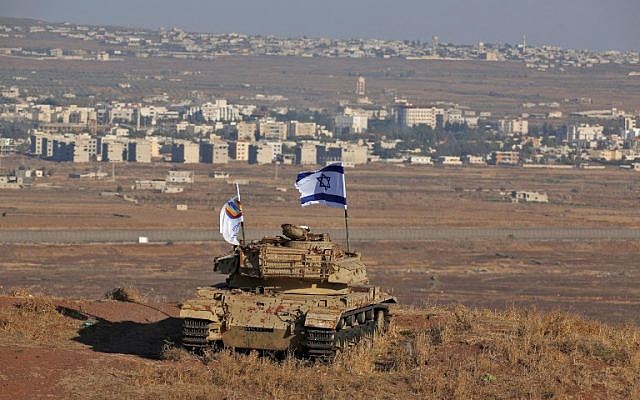 An Israeli flag flutters above the wreckage of a tank on a hill in the Golan Heights overlooking the border with Syria on October 18, 2017. (AFP Photo/Jalaa Marey)
