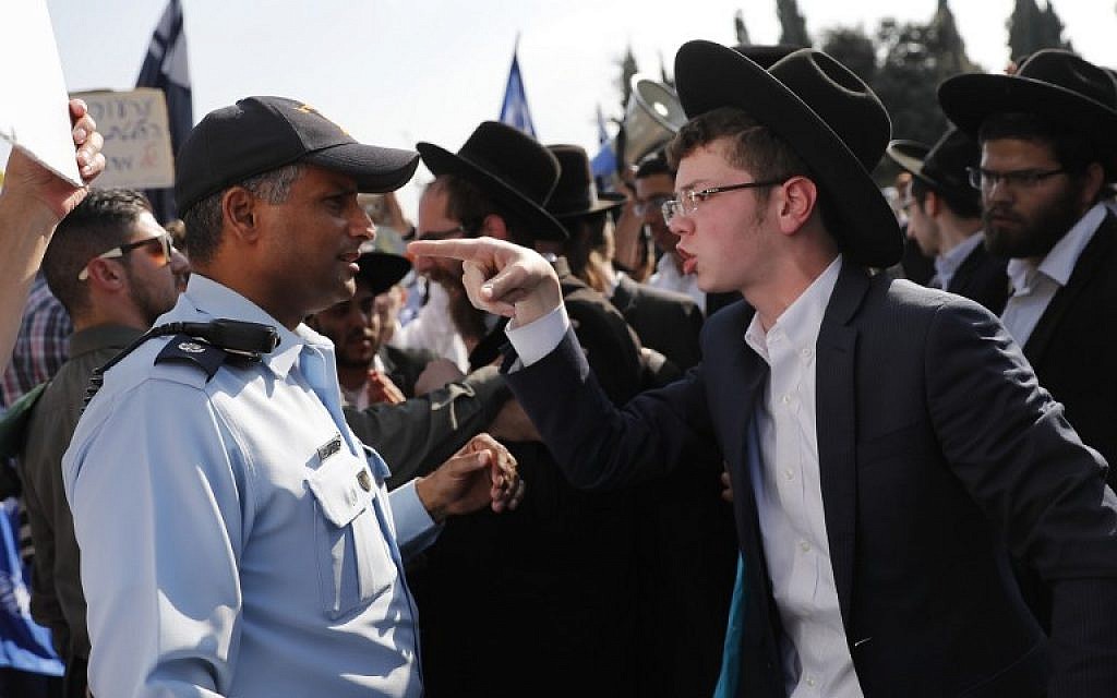An ultra-Orthodox Jewish demonstrator points towards at a policeman during a demonstration against the conscription of ultra-Orthodox Jews community to the IDF outside the Knesset in Jerusalem on October 23, 2017. (AFP Photo/Thomas Coex)