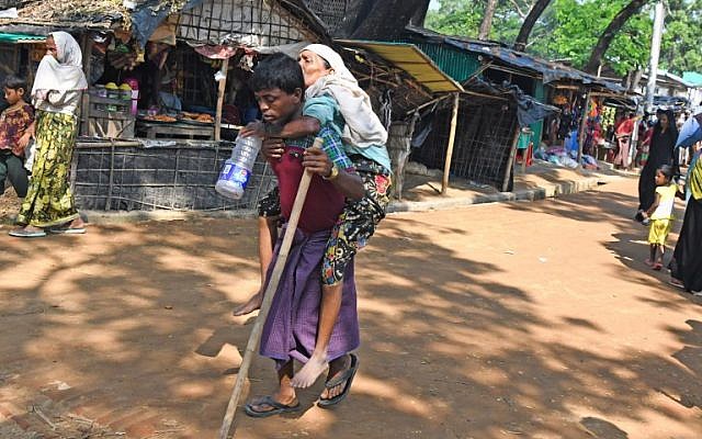 A Rohingya refugee carries an elderly woman toward a makeshift shelter at Kutupalong refugee camp in the Bangladeshi district of Ukhia, October 26, 2017. (AFP/Tauseef MUSTAFA)