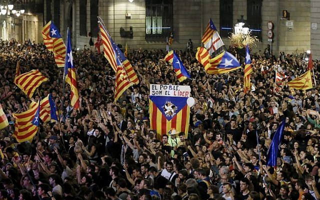 A flag with the text in Catalan "The people lead" is held up as people gather to celebrate the proclamation of a Catalan republic at the Sant Jaume square in Barcelona, on October 27, 2017. (AFP/Pau Barrena)