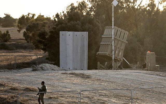 Illustrative: An Israeli soldier stands guard next to Israel's Iron Dome defense system, designed to intercept and destroy incoming short-range rockets and artillery shells, deployed close to the Israeli border with the Gaza Strip, near Kibbutz Kissufim in southern Israel, on October 30, 2017. (AFP Photo/Menahem Kahana)