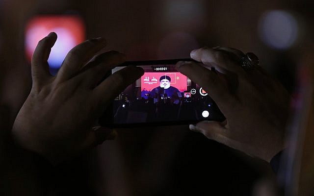 Hezbollah leader Sheik Hassan Nasrallah is displayed on a cellphone as he delivers a message via video link, during the ninth of Ashura, a 10-day ritual commemorating the death of Imam Hussein, in a southern suburb of Beirut, Lebanon, September 30, 2017.  (AP/Hassan Ammar)