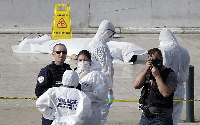 Investigative police officers work by a body under a white sheet outside Marseille's main train station Sunday, Oct. 1, 2017 in Marseille, southern France. A man with a knife attacked people at the main train station, killing two women before soldiers fatally shot him, officials said. (AP Photo/Claude Paris)