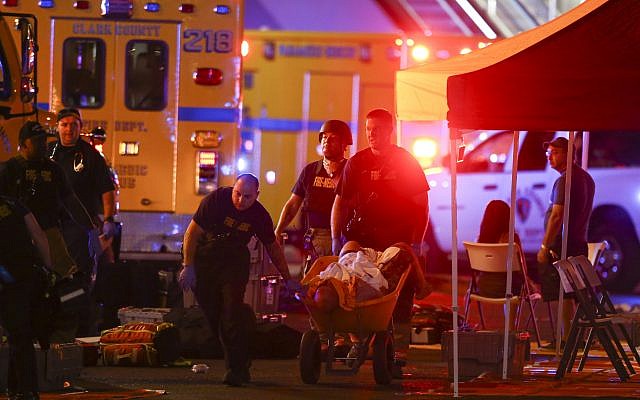 A wounded person is walked in on a wheelbarrow as Las Vegas police respond during an active shooter situation on the Las Vegas Strip in Las Vegas,  October 1, 2017. (Chase Stevens/Las Vegas Review-Journal via AP)