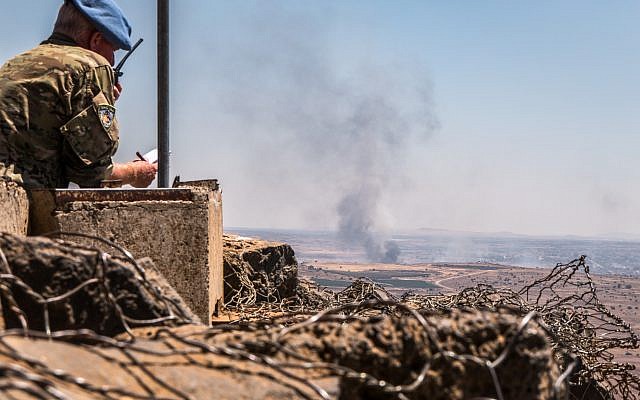 Illustrative photo of a UN observer at a lookout point as smoke rising at a Syrian village near the Israeli-Syrian border in the Golan Heights during fights between the rebels and the Syrian army, June 25, 2017. (Basel Awidat/Flash90)
