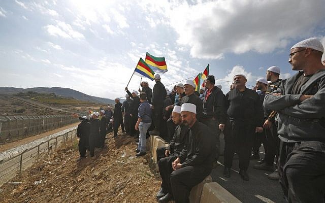 Druze men in the Israeli Golan Heights congregate near the Syrian border, waving their community's flag, after they heard about a suicide bombing in the Syrian Druze village of Hadar, on November 3, 2017. (Jalaa Marey/AFP)