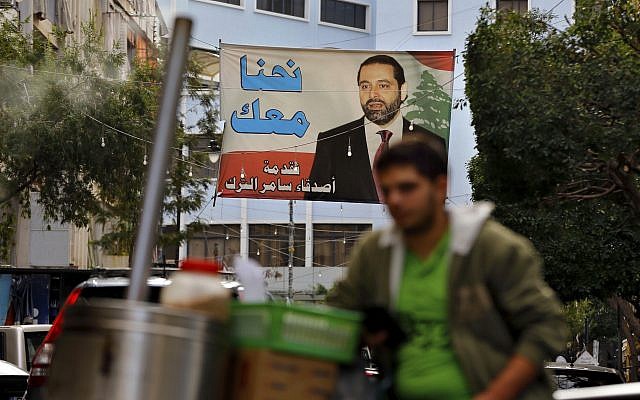 A street vendor stands in front of a poster of outgoing Prime Minister Saad Hariri, saying 'We are with you,' in Beirut, Lebanon, November 6, 2017. (AP Photo/Bilal Hussein)