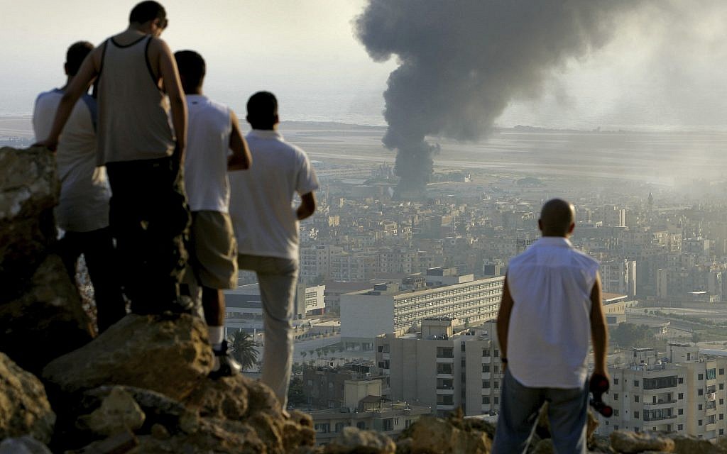 In this July 14, 2006 photo, Lebanese youths gather on a hilltop overlooking the city of Beirut in Lebanon at sunset to watch smoke continuing to billow from a fuel dump at Beirut International Airport, which was hit by an Israeli airstrike. (AP Photo/Ben Curtis)