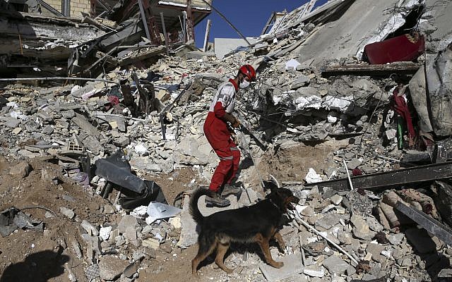 A rescue worker searches the debris with his sniffing dog on the earthquake site in Sarpol-e-Zahab in western Iran, Tuesday, November 14, 2017. (AP Photo/Vahid Salemi)