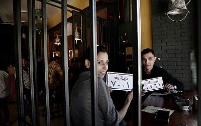 In this Nov. 22, 2017 photo, customer Amr El Gohary, right, and his friend pose for a photograph with plastic plaques with inmate numbers as they wait for their food at the prison-themed restaurant 'Food Crime' in the Nile Delta city of Mansoura, 110 kilometers (70 miles) north of Cairo, Egypt. (AP Photo/Nariman El-Mofty)