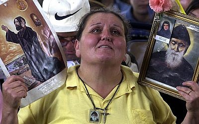Mary Iskandar, 50, a Lebanese housewife, is overcome by emotion, as she raises a picture of Maronite Naamatallah Kassab Hardini, left, and St. Charbel Makhlouf, Lebanon's first Maronite cleric to be canonized by the Vatican, in 1977, as Pope John Paul II, proclaims Hardini a saint of the Catholic Church at a ceremony at the Vatican on May 16, 2004.  (AP Photo/Mahmoud Tawil)
