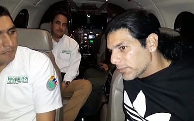 Screen capture from video showing alleged crime lord Assi Ben-Mosh, right, on a flight after being expelled from Colombia. (Screen capture: YouTube)