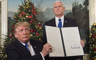 US President Donald Trump holds up a signed memorandum recognizing Jerusalem as Israel’s capital, as US Vice President looks on, at the White House, on December 6, 2017. (AFP Photo/Saul Loeb)