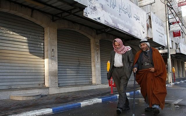 Illustrative: Palestinian men walk past closed shops in the West Bank city of Hebron as a general strike was called following US President Donald Trump's decision to recognize Jerusalem as the capital of Israel, December 7, 2017. (HAZEM BADER/AFP)