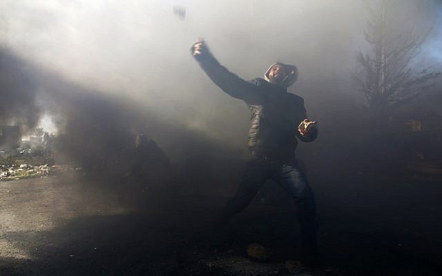 A Palestinian protester throws rocks at Israeli security forces near a checkpoint in the West Bank city of Ramallah on December 8, 2017. (Abbas Momani/AFP)