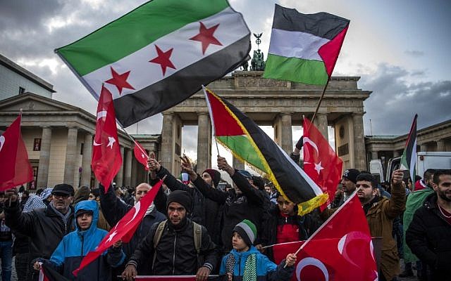 Demonstrators wave Palestinian, Turkish and Syrian flags in front of the Brandenburg Gate, next to the US embassy in Berlin on December 8, 2017, (AFP PHOTO / John MACDOUGALL)